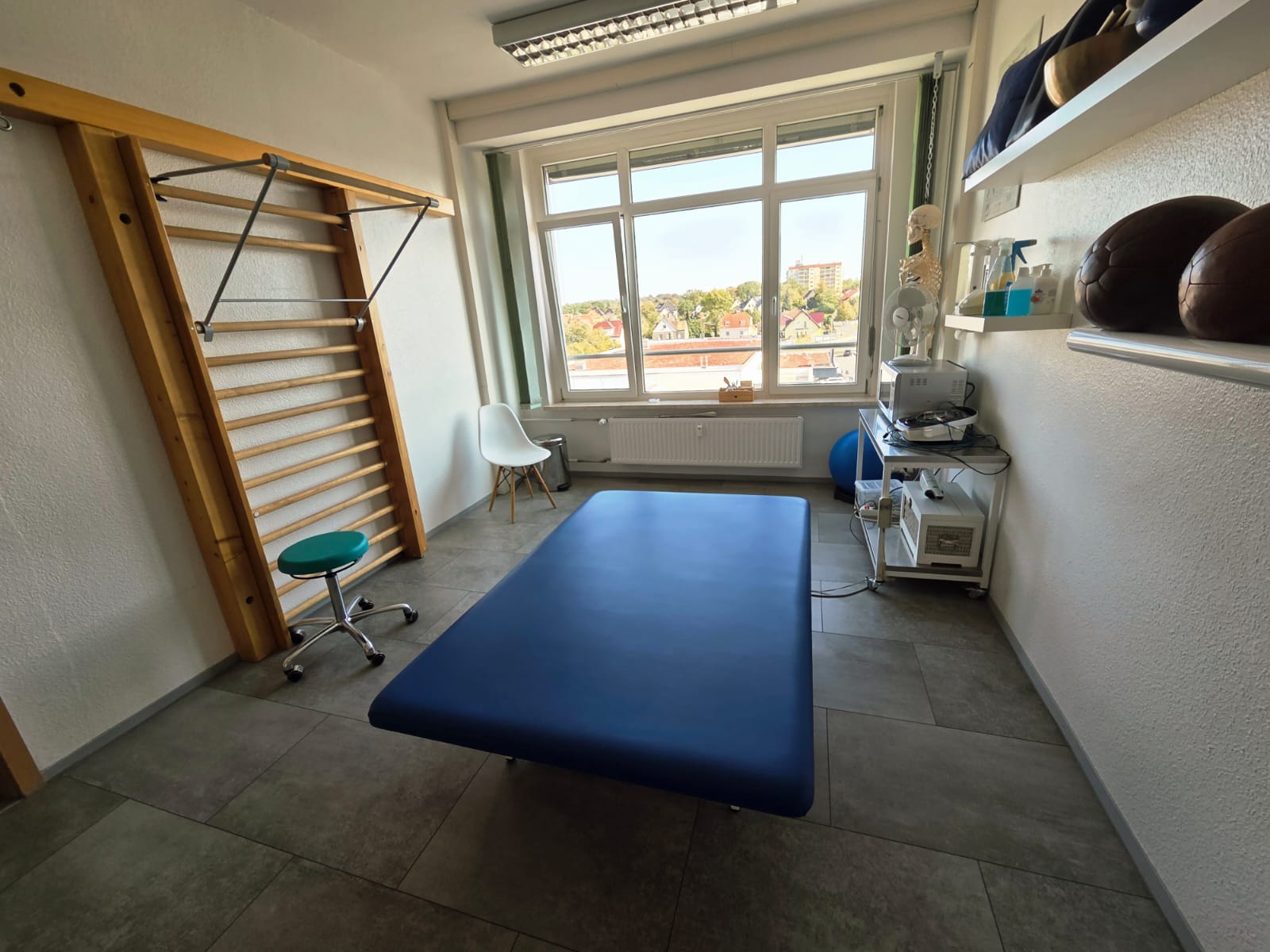 Neurotherapieraum mit blauer Behandlungsliege und Sprossenwand