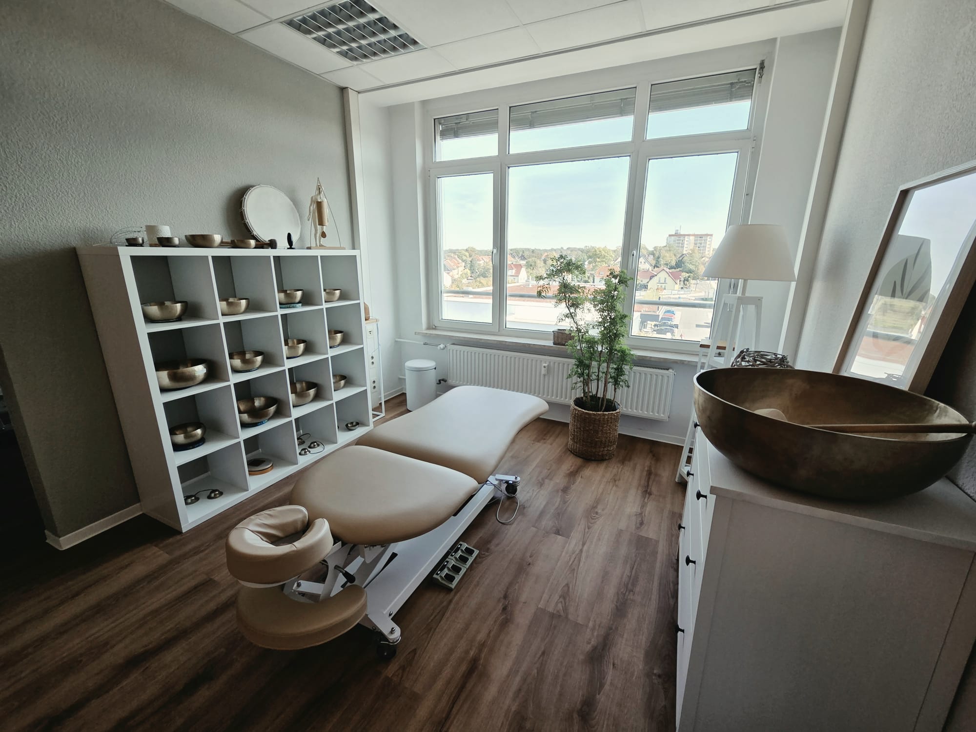 Heller Therapieraum mit Behandlungsliege und Klangschalen